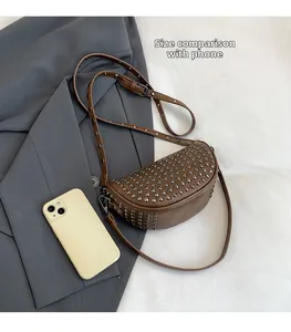 Detailed size comparison of dark brown punk rivet crossbody bag next to a smartphone