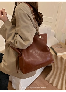 Detail of vintage dark brown leather tote featuring gold chain straps and drawstrings