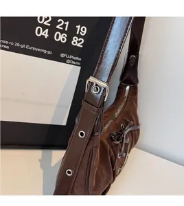 Close-up of brown suede shoulder bag featuring a decorative bow and adjustable strap