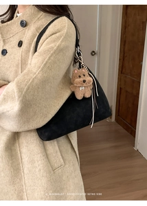 Detalle de bolso tote de ante negro con colgante de perro de peluche y estilo retro