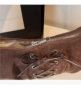 Detail of smooth silver zipper and criss-cross lacing on dark brown suede dumpling bag