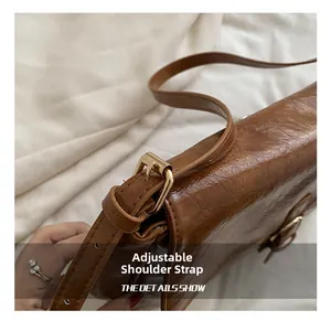 Macro shot of adjustable shoulder strap with gold-tone hardware on brown leather bag