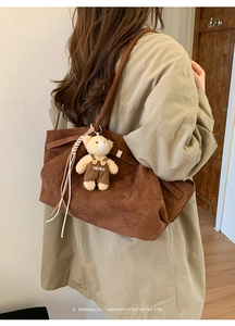 Detail of vintage brown suede tote bag with a cute bear charm and soft matte texture