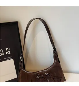 Detail view of dark brown suede hobo bag with leather bow and silver eyelet accents