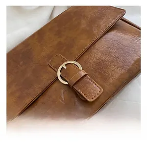 Macro shot of antique gold buckle on vintage brown cracked leather hobo bag detail