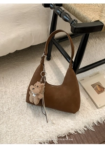 Detalle de bolso hobo de ante marrón oscuro con un lindo colgante de perrito