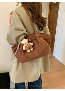 Detail of vintage brown suede tote bag with a cute bear plush charm and long shoulder straps