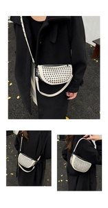 Close-up of white leather crescent bag with black studs and adjustable shoulder strap