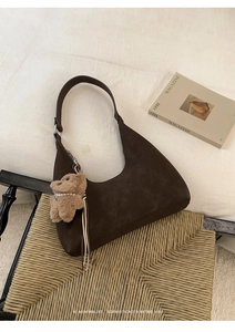 Primer plano del bolso hobo de ante marrón oscuro con colgante de oso y perlas