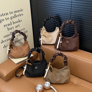 Minimalist dumpling handbags in multiple colors featuring unique gathered handles and charms