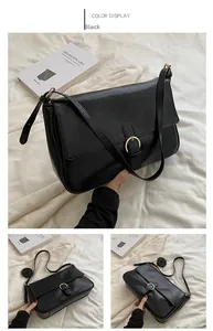 Detail view of black vintage PU leather crossbody bag with round gold buckle and strap