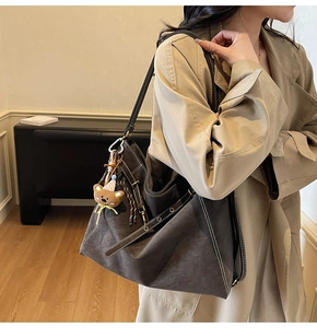 Detail of vintage coffee brown tote bag with white stitching and bear charm