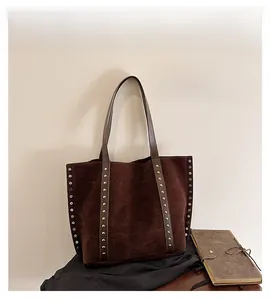 Detail view of large brown suede tote bag featuring silver studs and slender shoulder straps