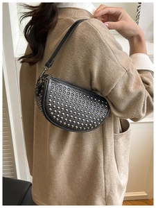 Detail of black leather crescent bag with silver stud rivets and a sleek zipper finish