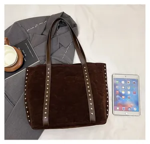 Detail of large dark brown suede tote bag with silver rivet studs and laptop for scale