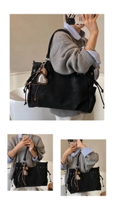 Detail of a black matte tote bag featuring drawstring sides and a leopard heart charm