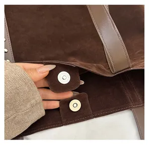 Detail view of the magnetic closure and suede texture on this brown tote bag