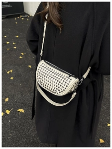 Detail of white crossbody bag with silver rivets on textured faux leather and zip closure