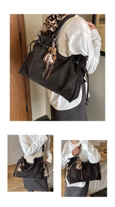 Detail of black large tote bag featuring leopard print scrunchie and heart charm