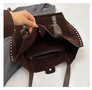 Detail view of large suede tote bag featuring silver studs and spacious inner pocket