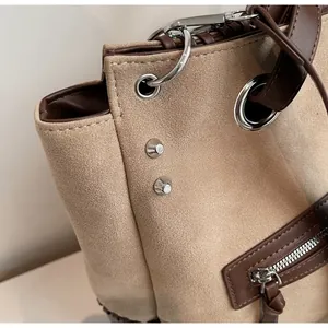 Dettaglio macro di cuciture in camoscio beige con finiture in pelle marrone e rivetti
