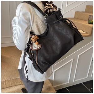 Detail of black large-capacity tote bag with leopard scarf and heart pendant