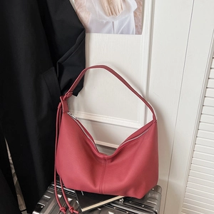 Detail of watermelon red hobo bag showing soft leather texture and knotted strap detail