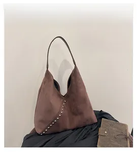 Detail of dark brown suede shoulder bag with silver rivet studs and diagonal stitching