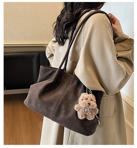 Detail view of large dark brown suede tote bag with a cute puppy plush charm pendant