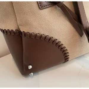 Vista macro delle cuciture in pelle e dei piedini metallici su una borsa a tracolla retrò
