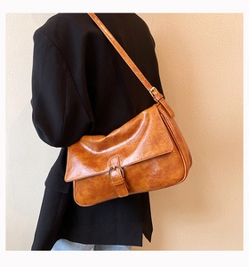 Close-up of vintage brown oil wax leather shoulder bag with metallic buckle detail