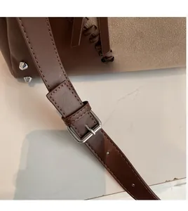 Dettaglio di cuciture a contrasto, rivetti argento e tracolla in pelle di una borsa tote