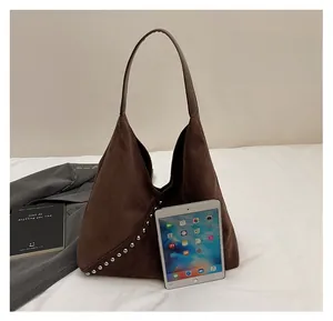 Brown suede tote bag with metal studs compared to an iPad showing large capacity