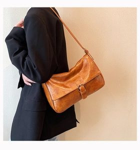 Detailed side view of a vintage caramel brown faux leather shoulder bag on a black blazer