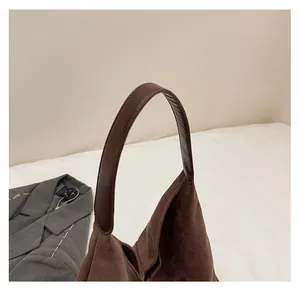 Detailed close-up of durable leather handles on a dark brown faux suede tote bag