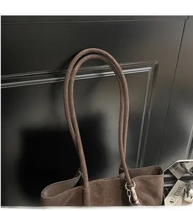 Close-up of durable long handles and smooth brown leather texture on a tote bag