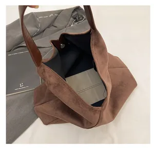 Macro view of large brown suede tote bag featuring a secure magnetic snap closure interior