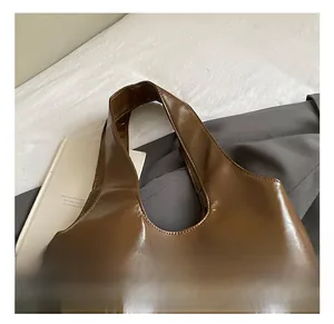 Close-up of brown leather tote handle and triangular metal hardware on side