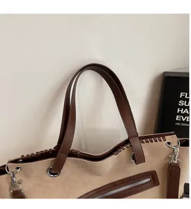 Dettaglio dei manici in pelle e cuciture intrecciate su una borsa tote beige vintage