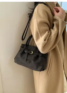Detail of dark brown suede shoulder bag with gold metal buckle and leather strap