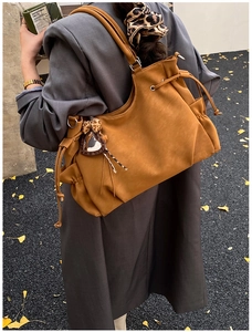 Macro detail of camel tote bag with drawstring closure and leopard heart charm