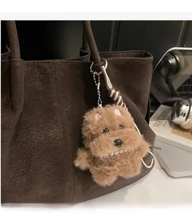Brown plush dog keychain charm with pearl necklace attached to a leather tote bag