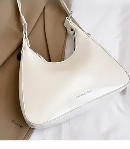 Detail of white half-moon underarm bag with silver hardware on khaki coat background
