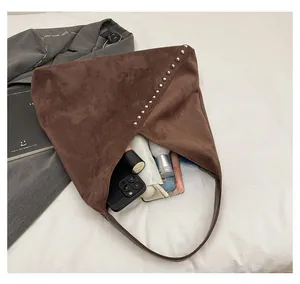 Detail of spacious interior capacity in dark brown suede tote bag with silver metal rivets