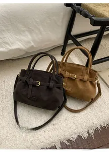 Detail of suede crossbody bags in dark coffee and caramel with vintage gold buckles