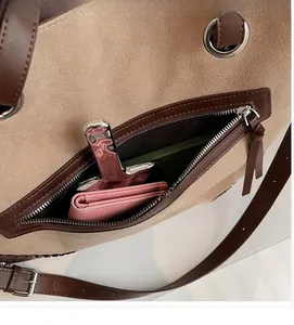 Dettaglio della borsa tote in camoscio beige con finiture in pelle marrone e tasca con zip