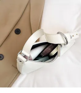 Internal storage view of white half-moon bag with daily essentials and silver ring detail
