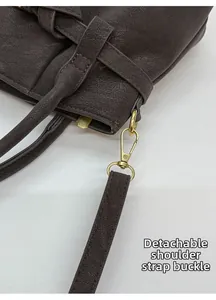Close-up of golden metal lobster clasp and brown pebble leather strap on a handbag