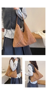 Detailed view of brown suede tote bag featuring silver rivet studs and slim shoulder straps