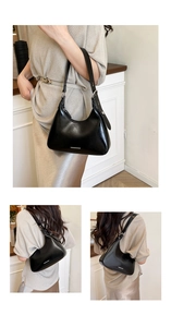 Detail of black glossy crescent shoulder bag with wide strap and fashion lettering